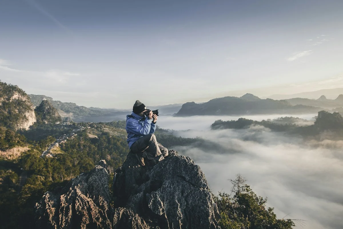 A photographer on a rock overlooking a mountain landscape
