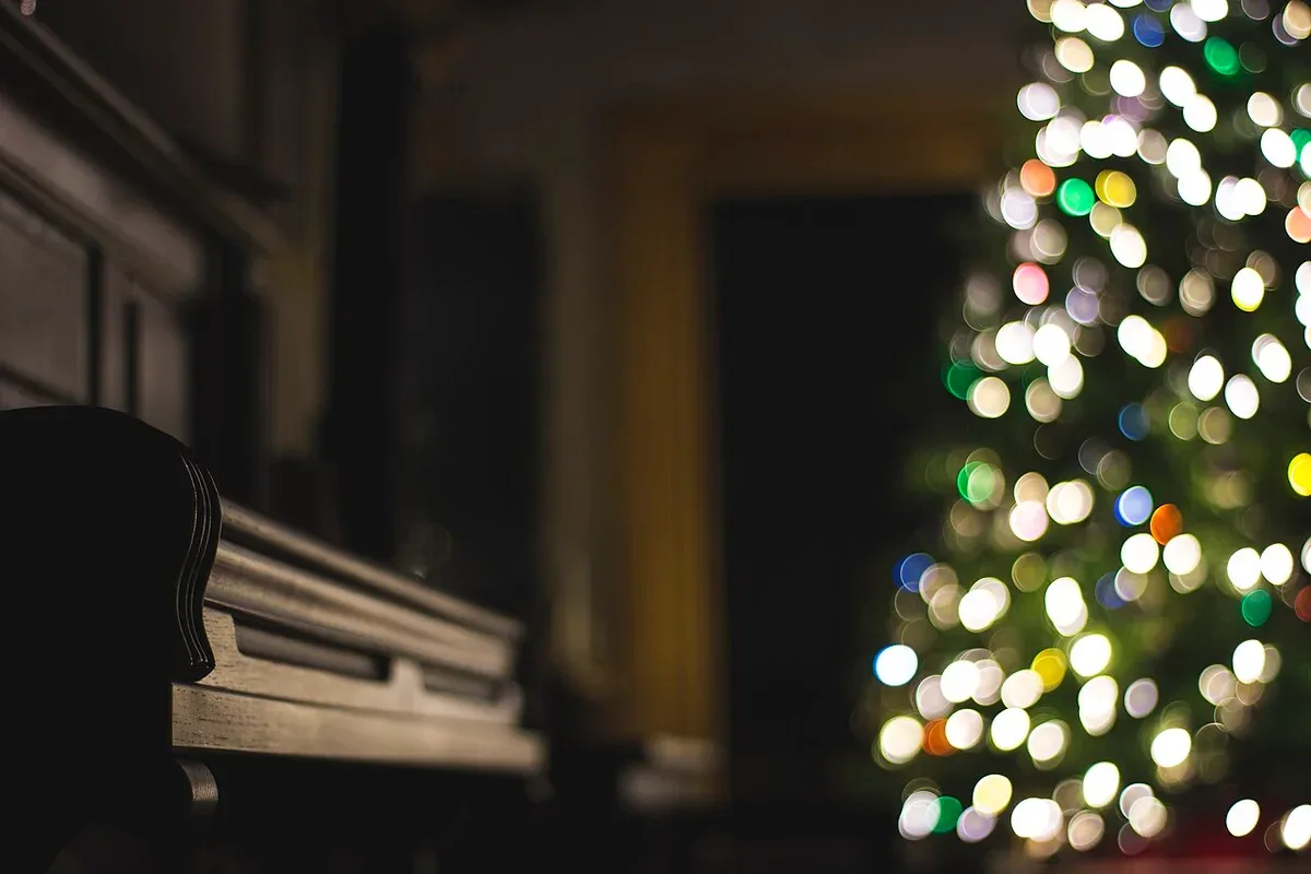 Klaviertasten neben sanft beleuchtetem Weihnachtsschmuck