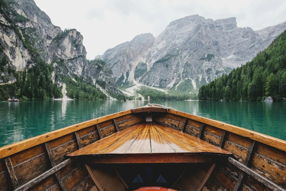 A wooden boat beside a lake with mountains in the distance