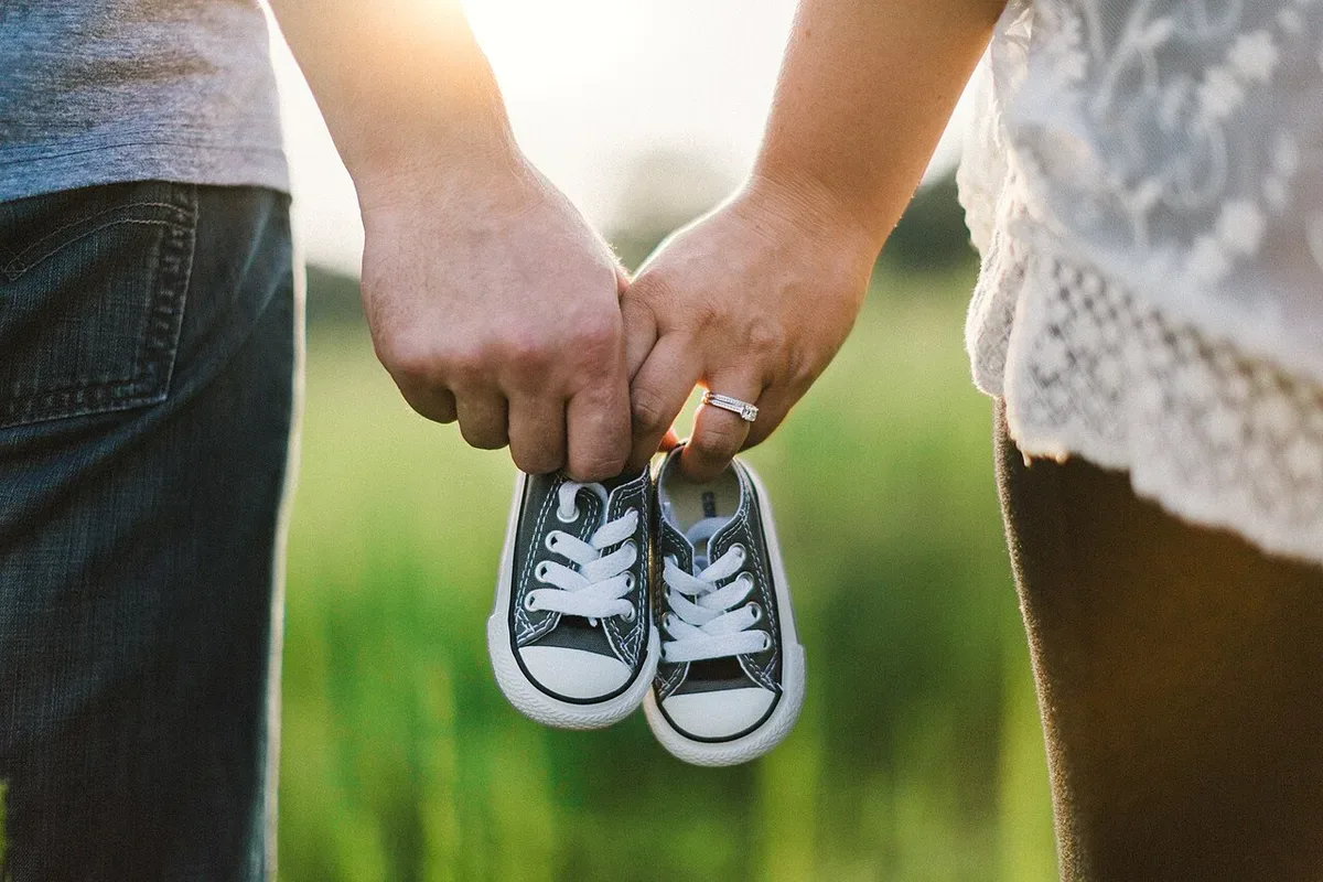 Two people holding a pair of baby shoes