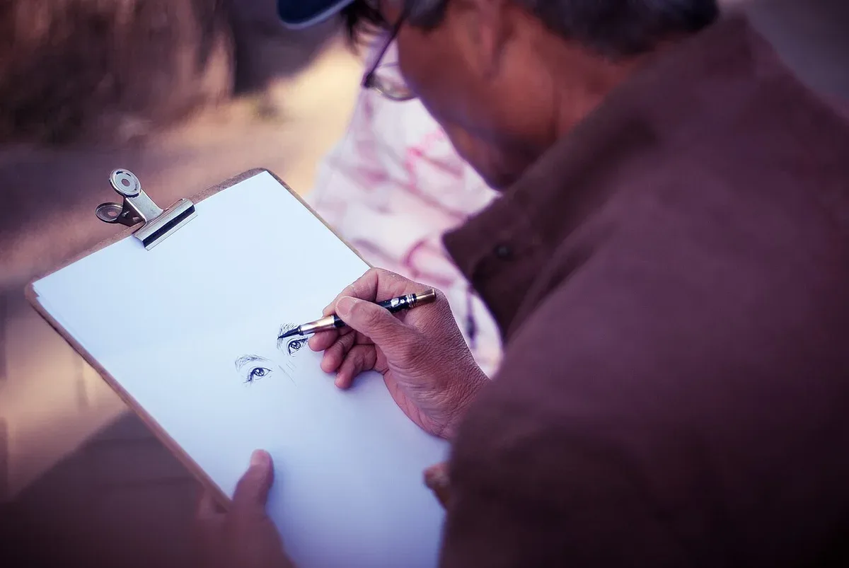 An artist drawing on a clipboard outdoors