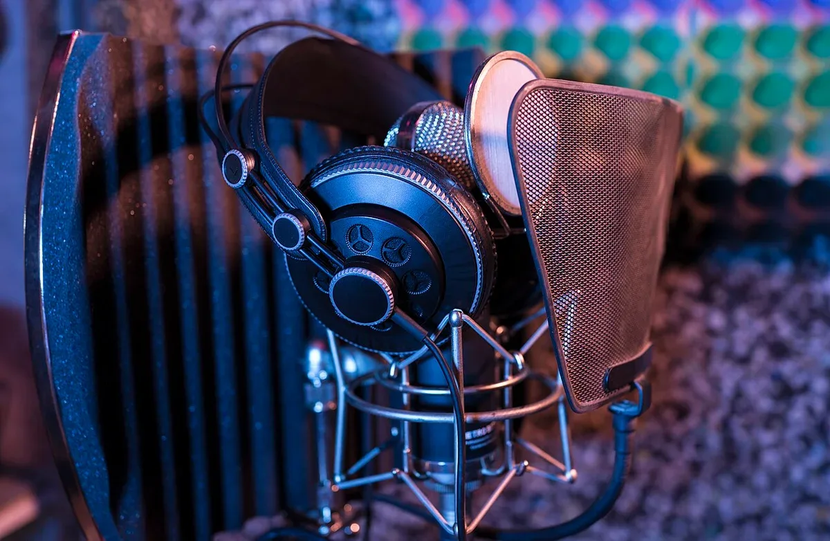 Headphones hanging beside a microphone and pop filter