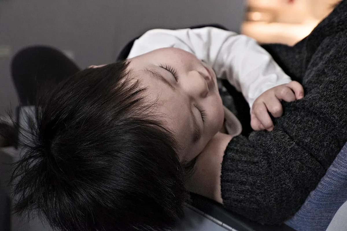 A baby resting against an adult's shoulder