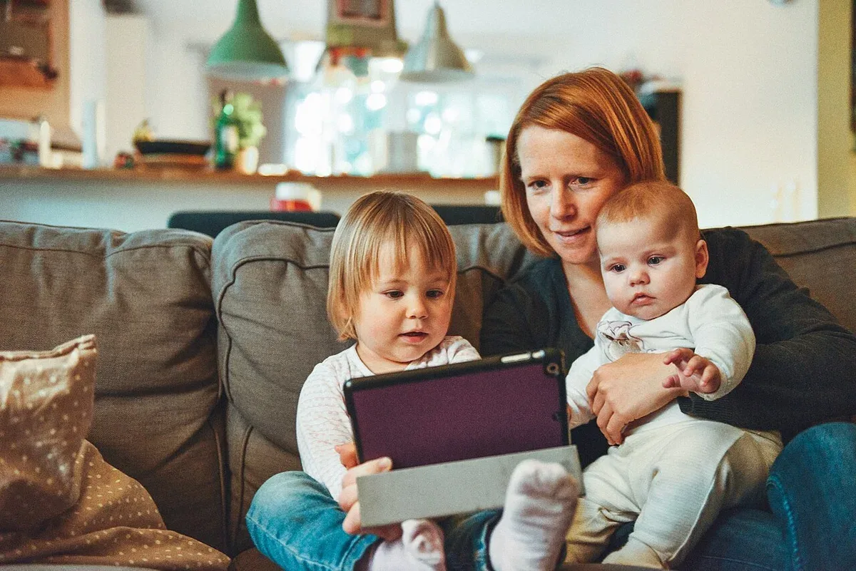 An adult and two children sharing a book on a sofa
