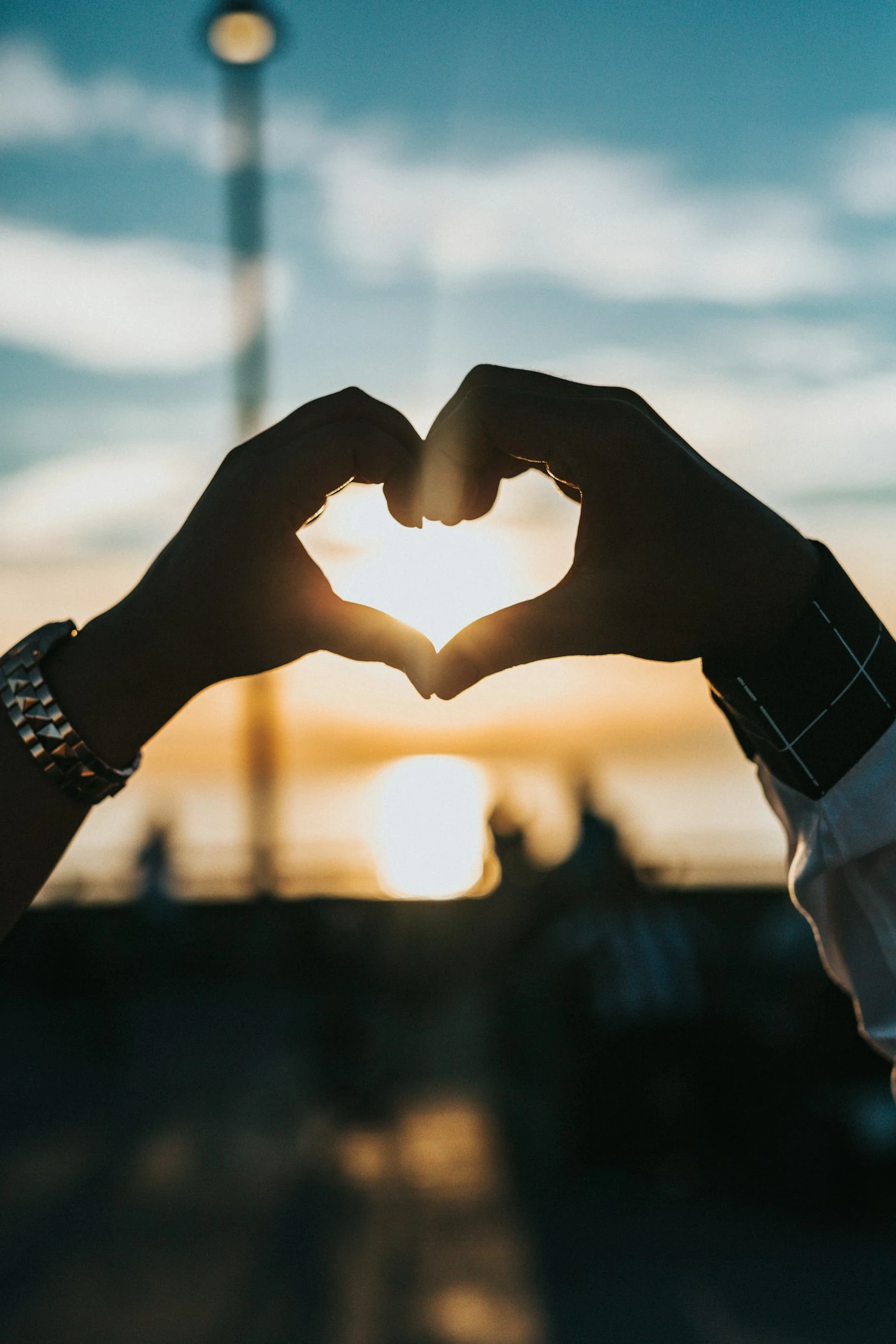 Hands forming a heart in front of the setting sun