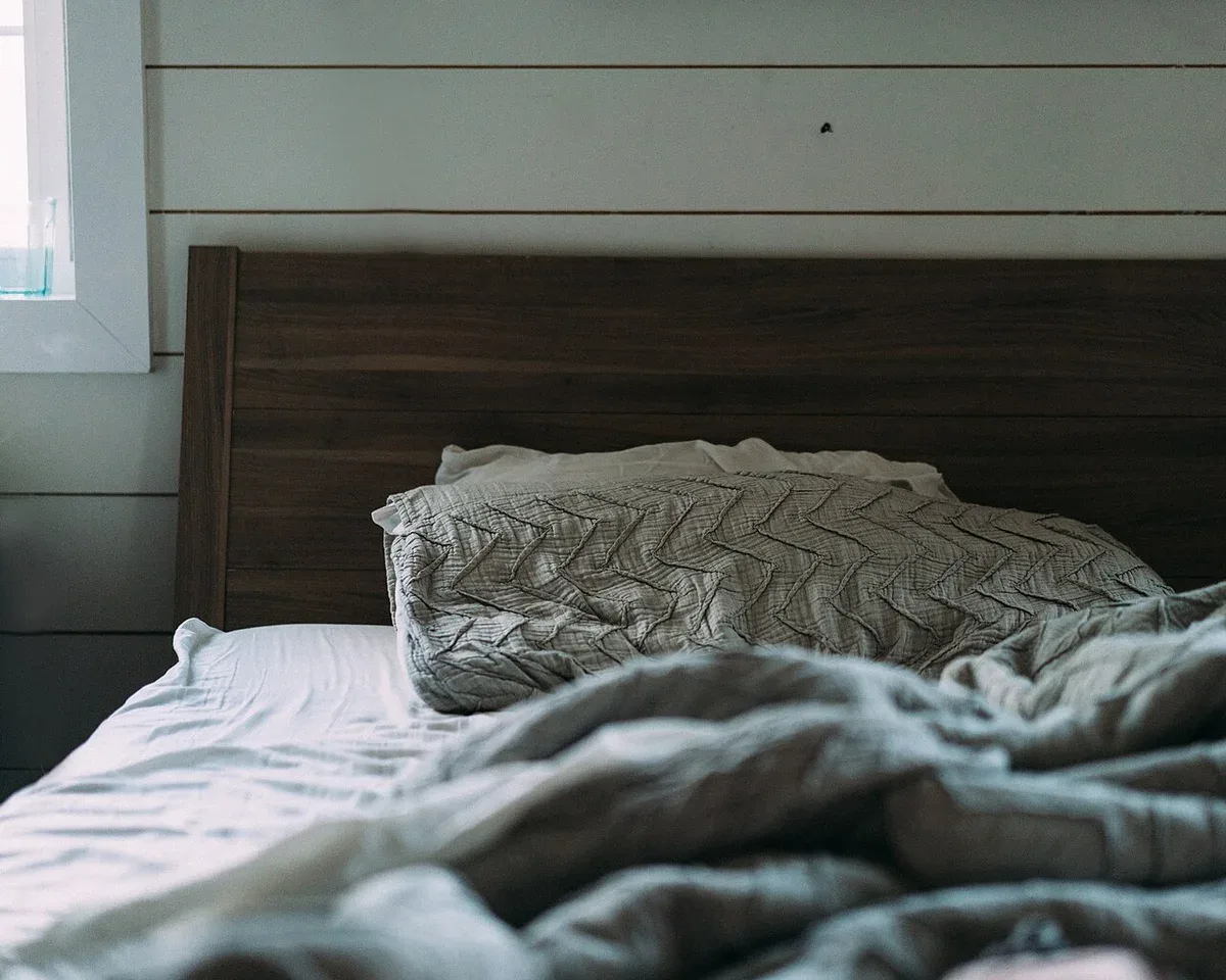 Soft bedding and pillows beneath a dark wooden headboard