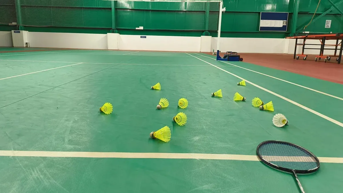 Badmintonová raketa a košíčky na krytém kurtu