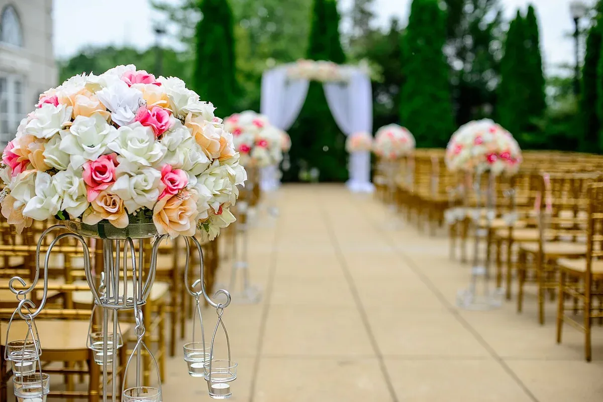 Flowers and rows of chairs beside an outdoor wedding aisle