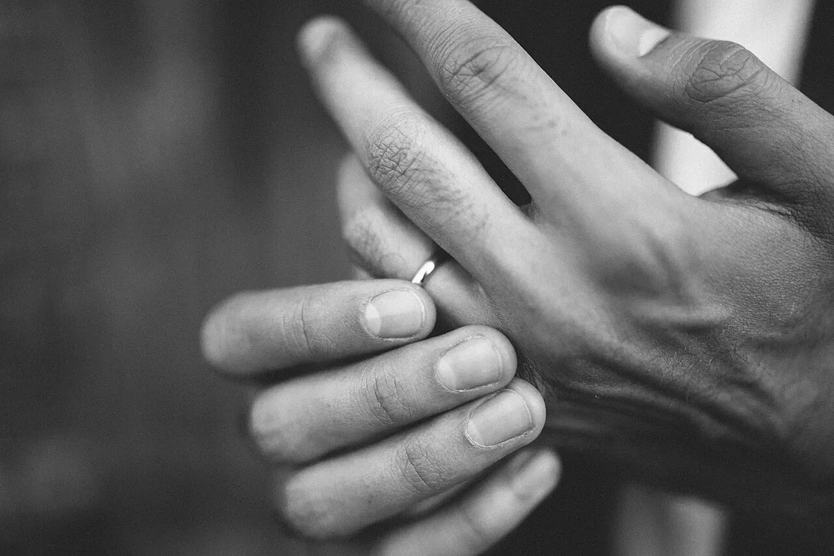 A close view of hands touching a wedding band